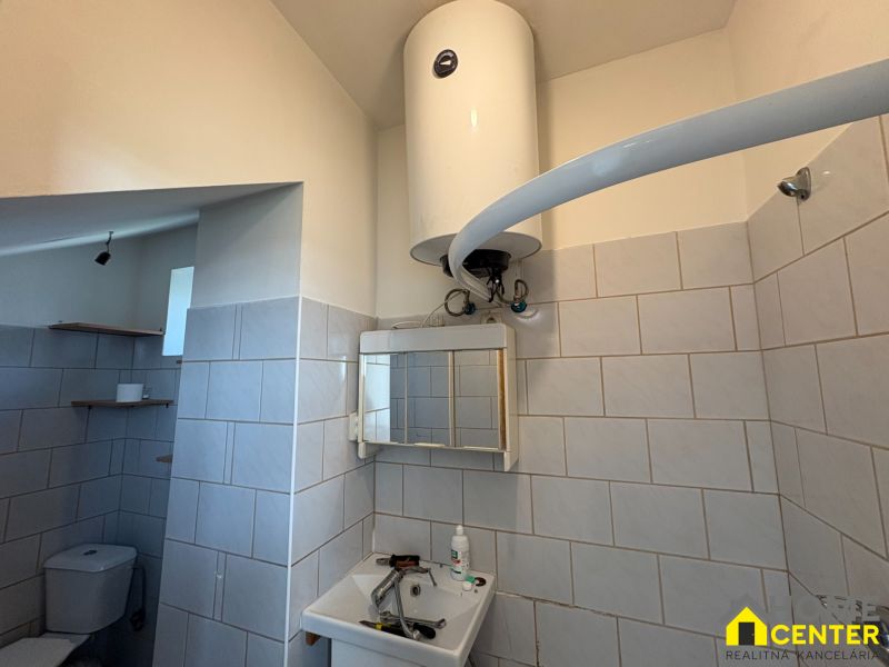Bathroom in a family house with tiled walls, a mirror, and an electric boiler.