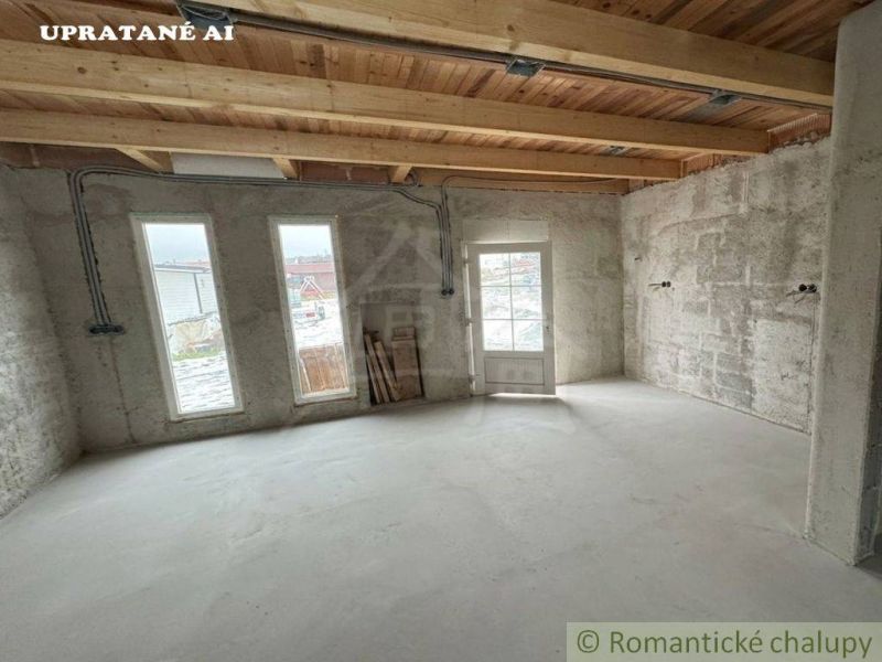 A room in a cabin with a concrete floor and a wooden ceiling, glass doors and windows.