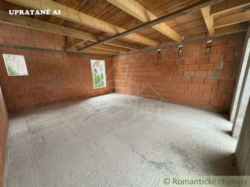 The interior of an unfinished cabin with a concrete floor and brick walls.