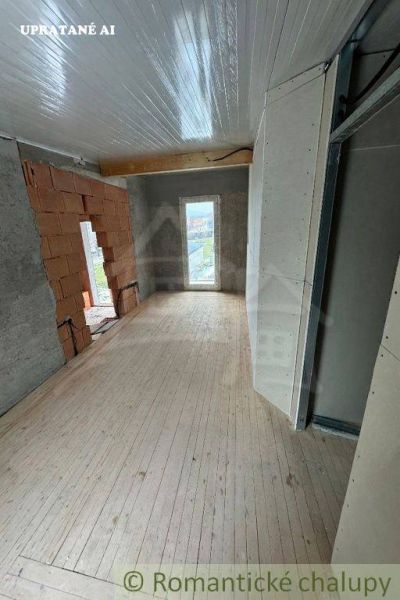 The interior of a cabin with a wooden decor floor and incomplete walls.