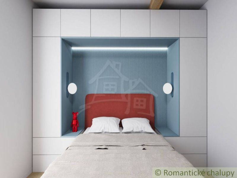 A double bed with a red headboard set between white wardrobes in the cottage.