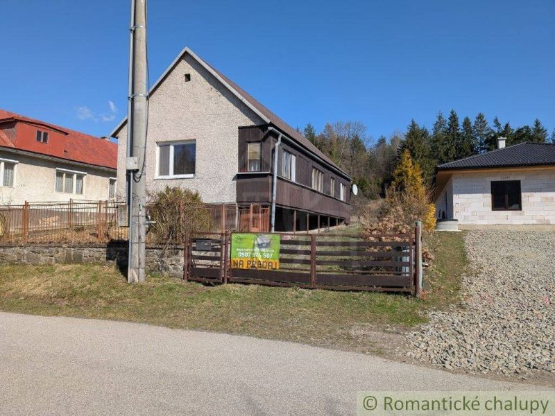 Family house in Kalinovo with wooden cladding, fence, and surrounding nature for sale.