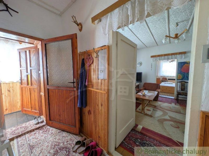 Interior of a family house with corners, shoes on the floor, and wooden wall paneling.