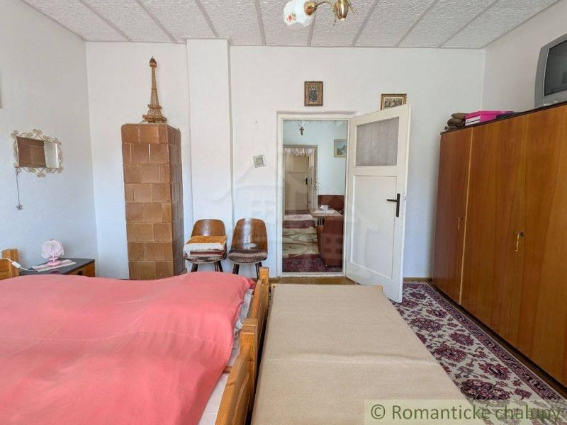 A bedroom in a family house with antique furniture and a tiled stove.