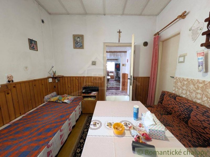 A living room in a family house with wooden paneling and simple furnishings.