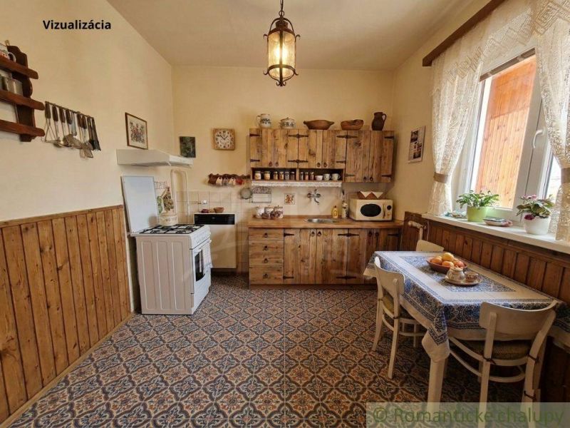 A kitchen in a family house with wooden furniture, tiled floor, and lace curtains.