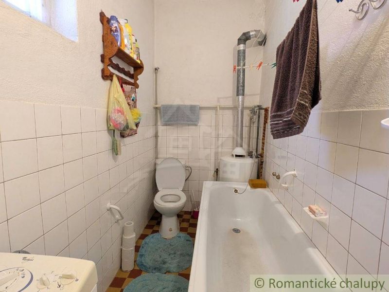 Bathroom in a family house with a bathtub, toilet, and white tiles on the walls.