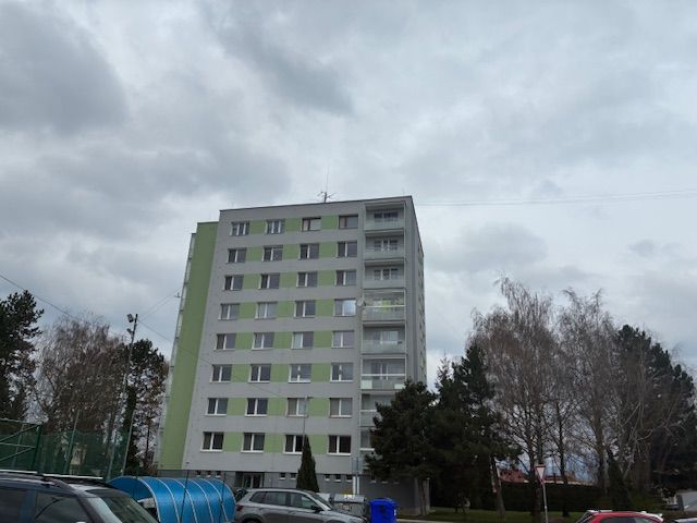 Apartment building on SNP Street in Ilava, surrounded by trees and parked cars.