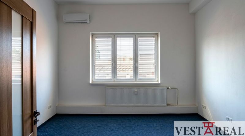 A room with air conditioning and a window in the offices, blue carpet, white walls.