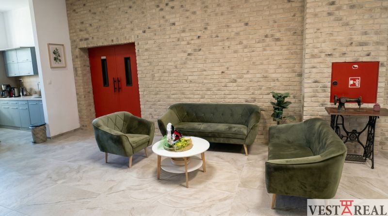 Spacious office with sofas, kitchenette, and brick wall.