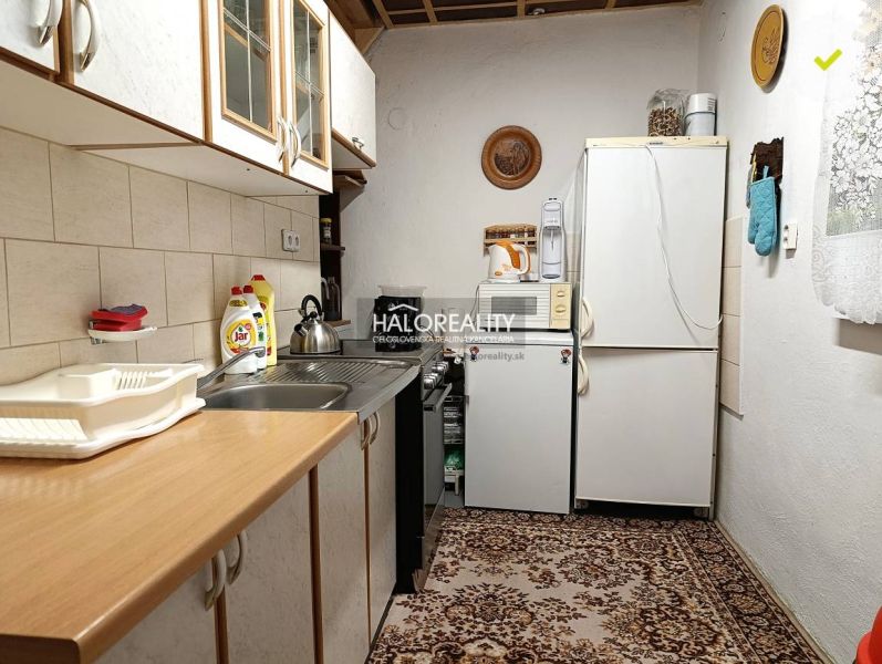 A kitchen in a cabin with carpet, equipped with appliances and wooden cabinets.