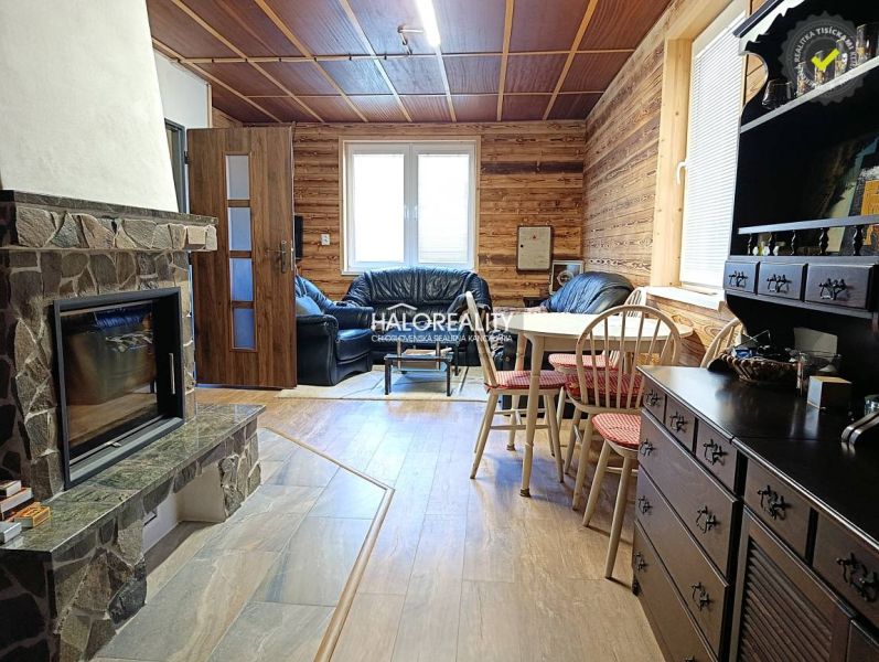 The interior of a cottage with a tiled stove, a leather sofa, and a floor with a wooden decor.