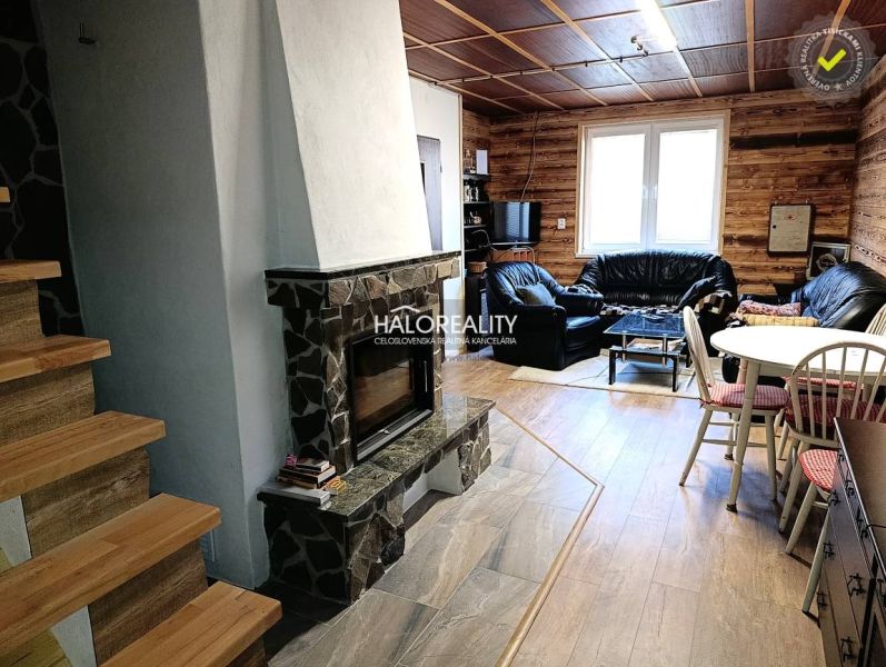 Interior of a cabin with a fireplace, leather sofas, and a floor with a wooden decor.