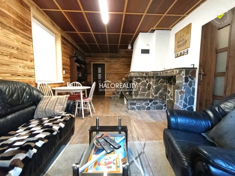 The interior of a cabin with a wooden decor floor, a stone fireplace, and a leather sofa.