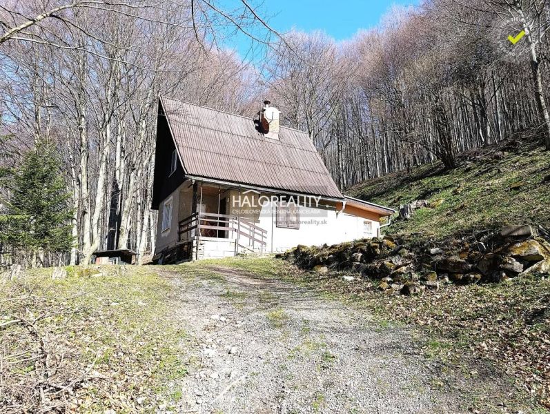 A cabin in Lehoty pod Vtáčnikom in the middle of the forest with a wooden terrace and a steep roof.