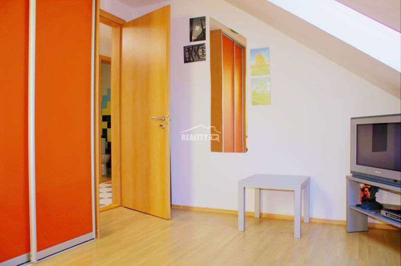 Interior of a holiday apartment with a wood-patterned floor, a television, and an orange cabinet.