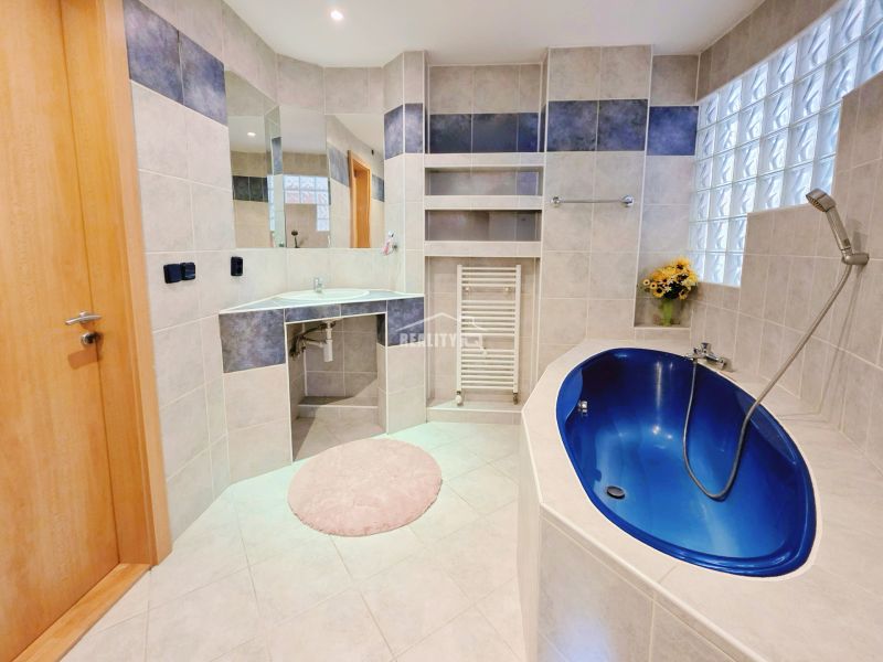 A bathroom in a holiday apartment with a blue bathtub and a glass partition.