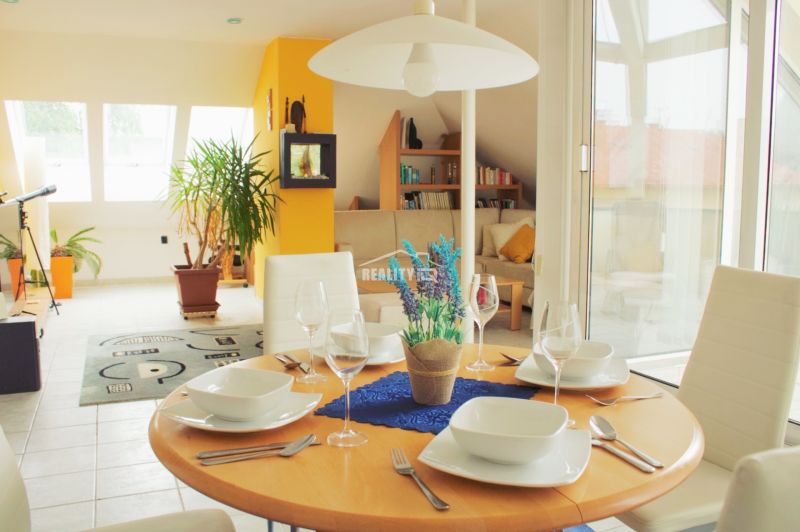 Interior of a holiday apartment with a dining table, plants, and a view of the living area.