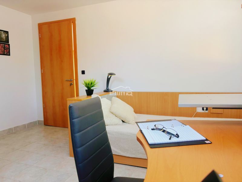 Interior of a holiday apartment with a wooden decor floor, a work desk, and cream seating.