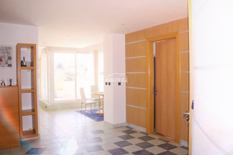 Interior of a holiday apartment with wood-patterned flooring and large windows for natural light.