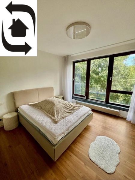 A bedroom with a light bed and a wooden decor floor in a 2-room apartment.