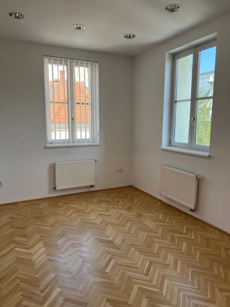 The interior of an office with parquet flooring and windows on Štefánikova Street.
