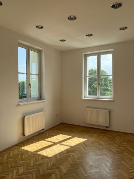 A room with parquet flooring, two windows, and lighting on Štefánikova Street. Suitable for offices.