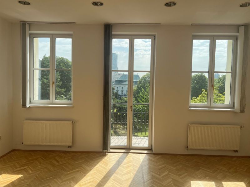 An empty room with parquet flooring, large windows, and a view of Štefánikova Street, suitable for offices.