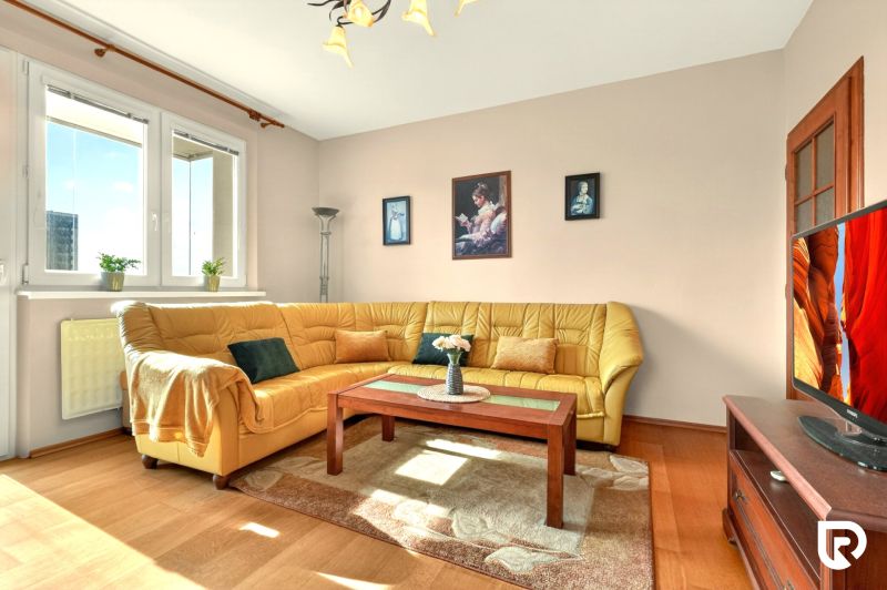 Living room in a 3-room apartment with a corner sofa and a wooden decor floor.