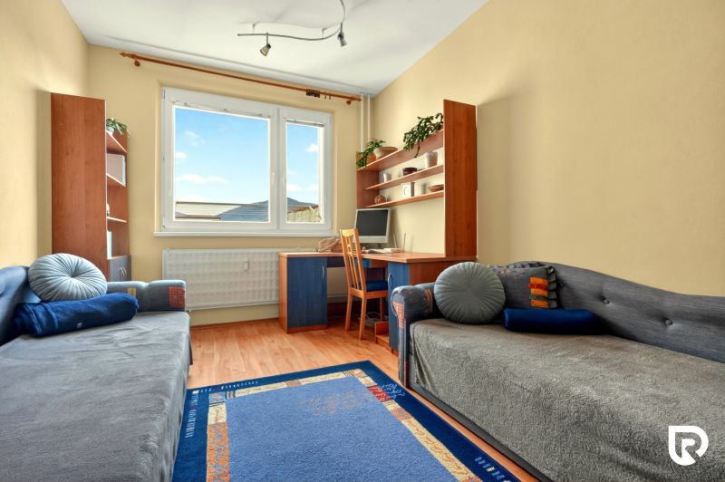 A room with carpets and a wooden decor floor in a three-room apartment, furnished with relaxation furniture.