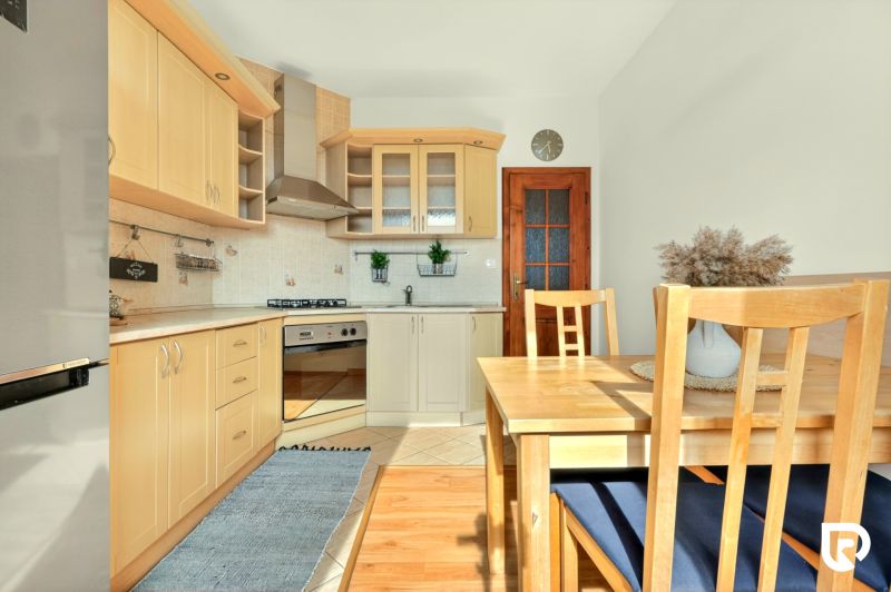 A kitchen in a 3-room apartment with a wooden decor floor and wooden furniture.