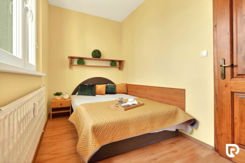 A bedroom in a 3-room apartment with a bed, a shelf, and a wooden decor floor.