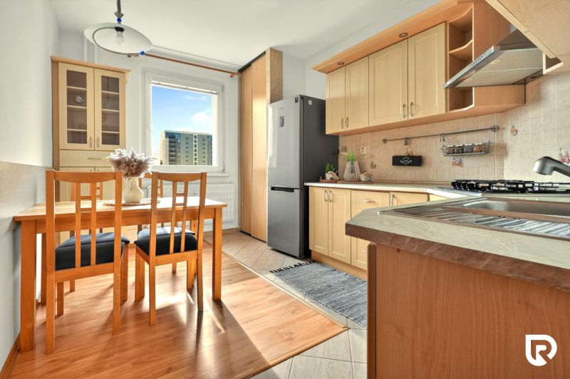 A kitchen with a wooden decor floor and a dining table in a 3-room apartment.