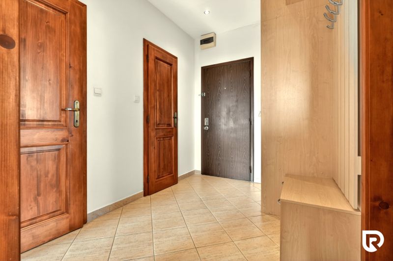 A hallway in a 3-room apartment with wooden doors and a coat rack.