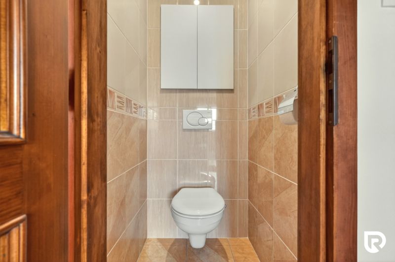 A toilet with beige tiles in a 3-room apartment.