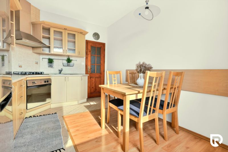 A kitchen in a 3-room apartment with wooden chairs and a floor with a wooden decor.