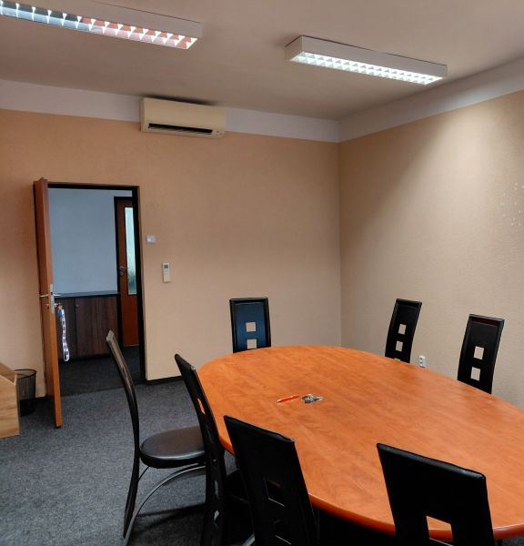 Oval table with black chairs in an office and a carpet.