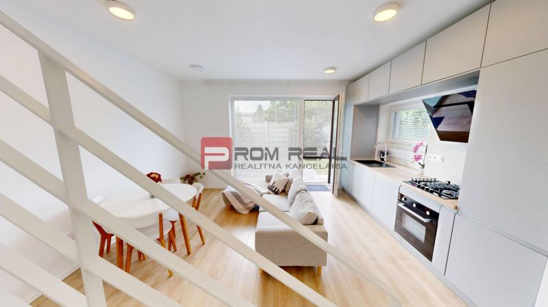 Interior of a 3-room apartment with wood-patterned flooring, kitchen unit, and sofa set.