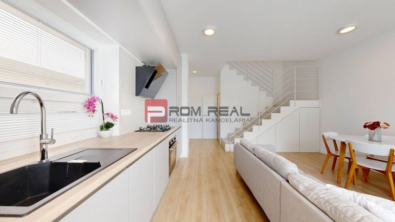 A kitchen in a 3-room apartment with a wood-patterned floor and a counter, staircase in the background.