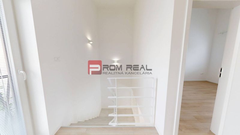 An interior with white walls, a staircase, and a floor with a wooden decor in a 3-room apartment.