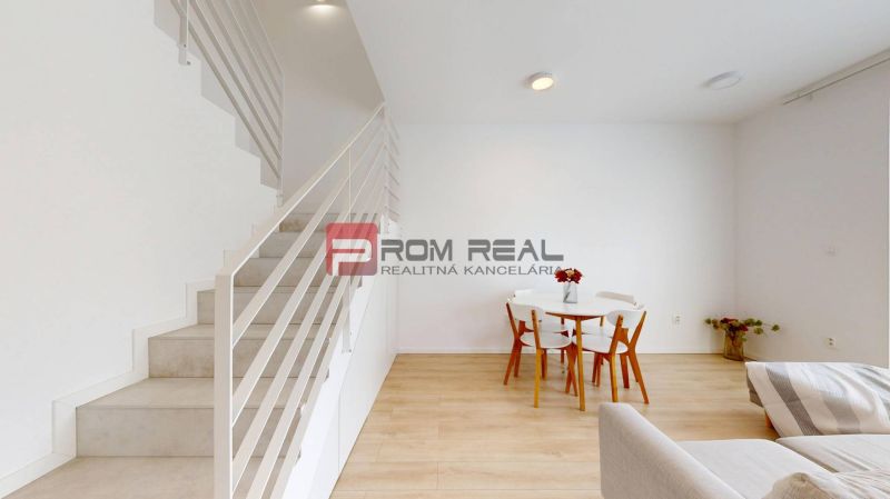 Interior of a 3-room apartment with wood-patterned flooring, stairs, and a dining table.
