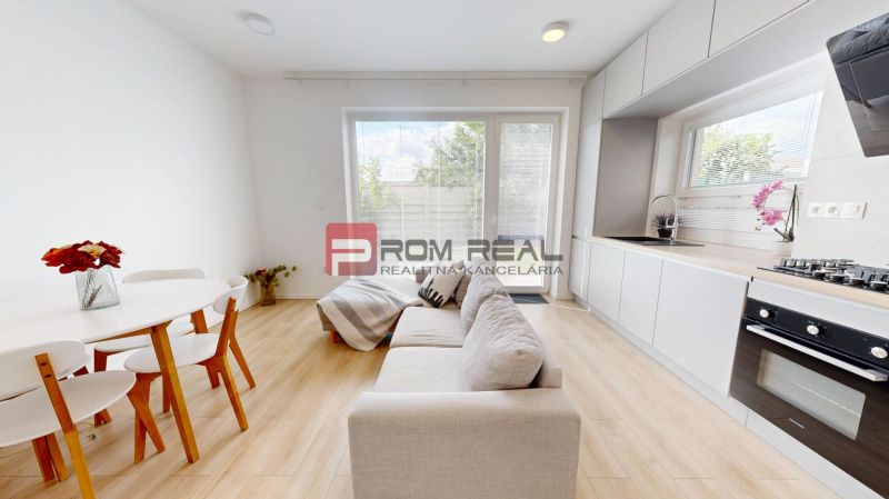 Bright kitchen in a 3-room apartment with a sofa, dining table, and large windows.