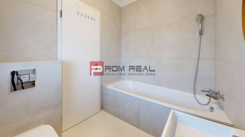 A minimalist bathroom with a bathtub and light tiles in a 3-room apartment.