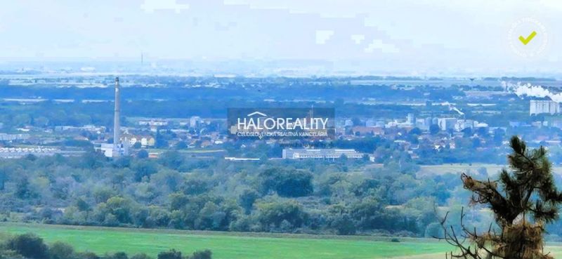 A panoramic view of the landscape around Hlohovec with greenery and a chimney in the background.