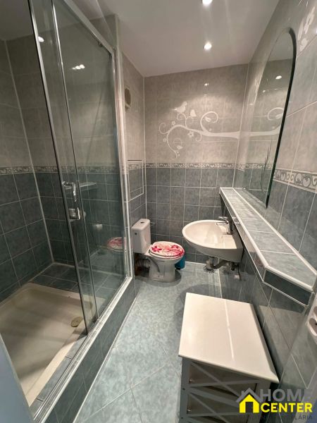 A bathroom in a studio apartment with a glass-enclosed shower and subtle tiling.