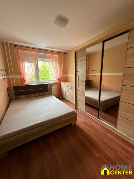 Bedroom in a studio apartment with a bed and a wardrobe, floor with wooden decor.