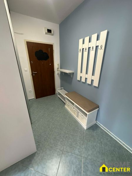 In the two-room apartment, a bright entrance with coat hooks and tiles, storage space with a seat.
