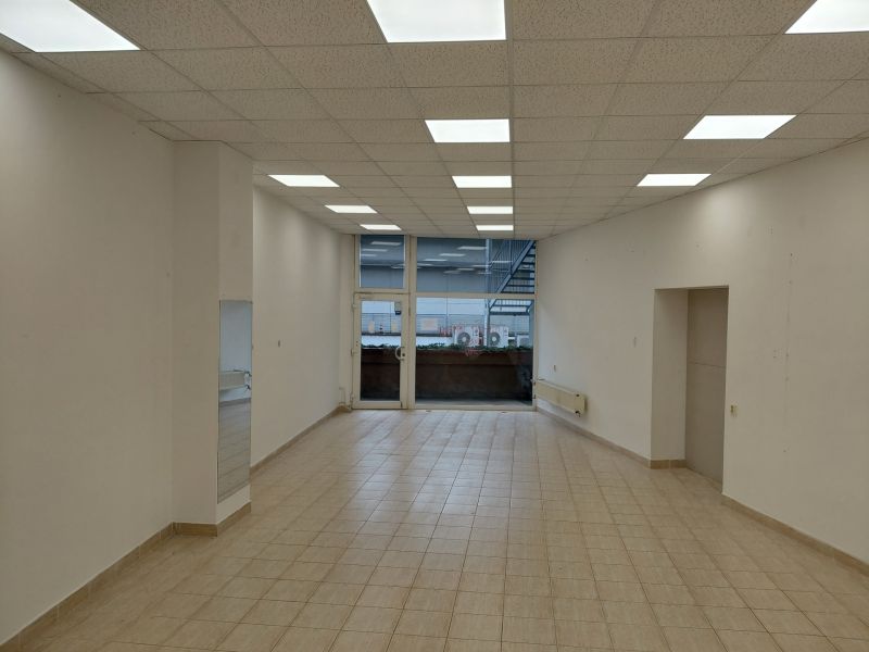 Commercial spaces with white walls, wood-patterned flooring, and large windows.