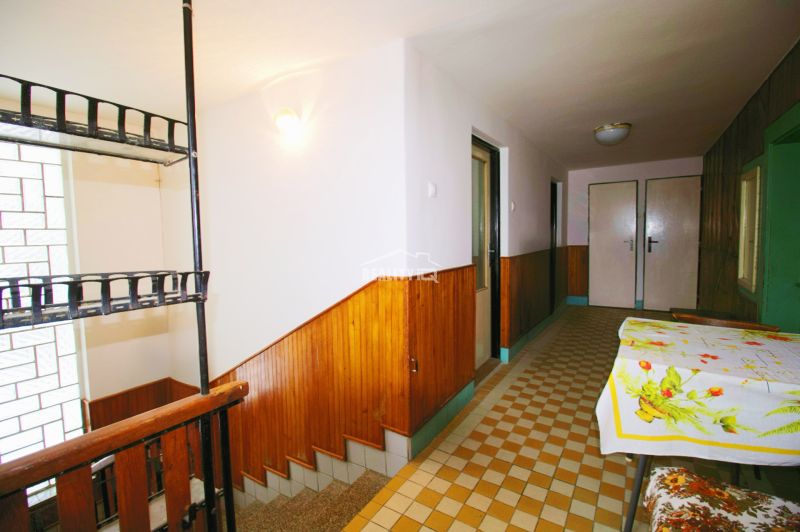 A hallway with a staircase and a table with a tablecloth in a family house.