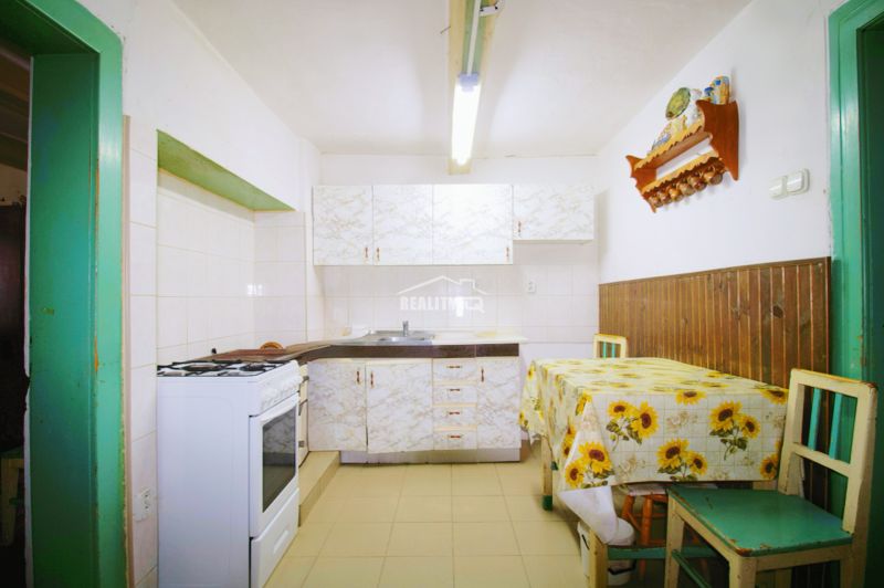 A kitchen in a family house with tiles and a table with a sunflower tablecloth.
